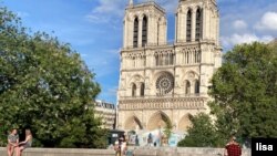 Some enjoy Notre Dame cathedral in Paris, mask-free, despite the city's surging cases. (Lisa Bryant/VOA)