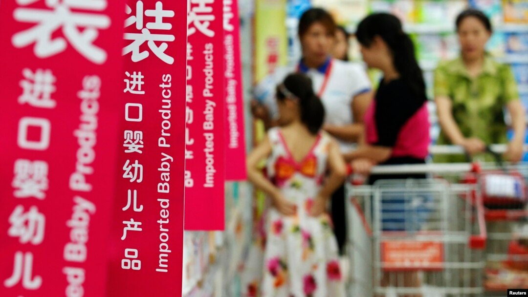 Customers talk to a sales assistant as they shop for milk powder in front of shelves displaying imported baby products at a supermarket in Beijing, August 5, 2013.