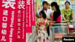 Customers talk to a sales assistant as they shop for milk powder in front of shelves displaying imported baby products at a supermarket in Beijing, August 5, 2013.