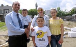 Hussam Alhallak, left, sons Danyal, held by his father, and Muhammad, wife Hazar Mansour and daughter Layan, right, stand by their new home being built by Habitat for Humanity of Rutland County in Rutland, Vt., July 31, 2019.