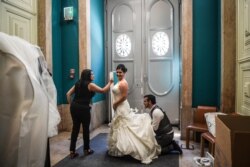 A bridal gown designer helps a bride to get dressed before a civil marriage ceremony at Lisbon's city hall, in Lisbon, Portugal, June 12, 2019.