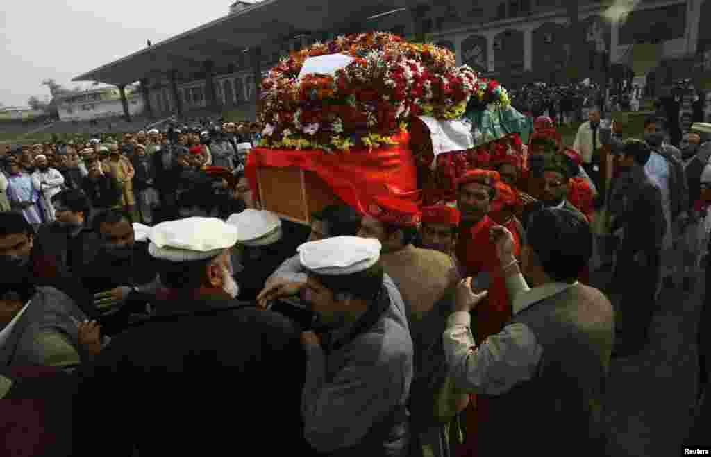People carry the coffin of the provincial minister for local government Bashir Ahmad Bilour, who died of his wounds from a bombing attack, during his funeral at the Army Stadium in Peshawar December 23, 2012. Taliban Islamic militants bombed a political r