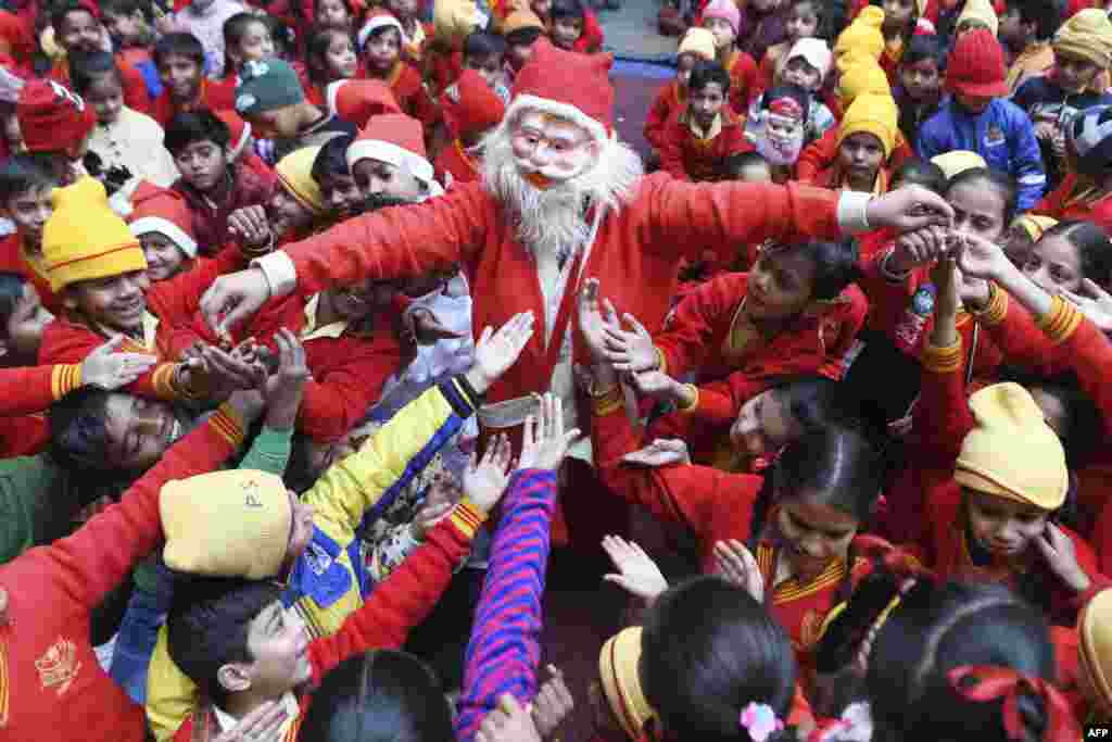 Seorang gadis berpakaian Sinterklas (Santa Claus) membagikan permen kepada anak-anak selama perayaan Natal di sebuah sekolah di kota Amritsar, India.