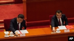Chinese President Xi Jinping, left, and his Premier Li Keqiang cast their vote during the closing session of the National People's Congress in Beijing, March 11, 2021, to endorse the latest move to tighten control over Hong Kong.