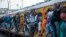 Train commuters hold on to the side of an overcrowded passenger train in Soweto, South Africa, Monday, March 16, 2020. 