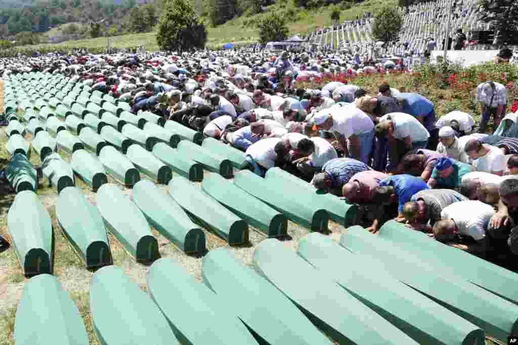 Bosnian people pray in front of coffins during a funeral ceremony for the 127 victims at the Potocari Memorial complex near Srebrenica, 150 kilometers (94 miles) northeast of Sarajevo, Bosnia and Herzegovina.