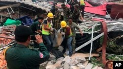 Rescue workers recover a body from the rubble of a collapsed building in Preah Sihanouk province, Cambodia Saturday, June 22, 2019. 