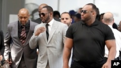 Musician R. Kelly, center, arrives at the Leighton Criminal Court building in Chicago for an arraignment on new sex-related felonies, June 6, 2019. 