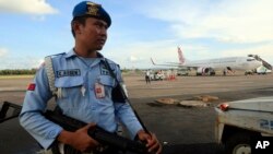 Un miembro de la fuerza aérea indonesia monta guardia cerca del avión de Virgin Australia que tuvo una emergencia en pleno vuelo.