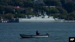 Seorang pria sedang duduk di sebuah perahu nelayan dekat peluru kendali China, Shangqiu, bersandar di Xiamen, Provinsi Fujian, China, 26 Desember 2023. (Foto: Andy Wong/AP Photo)