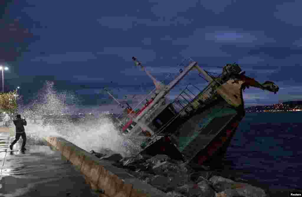 A man takes a picture of one of the ships that have been grounded on the shores of the Marmara Sea after extreme winds drove them off their moorings, in Istanbul&#39;s Maltepe district, Turkey.