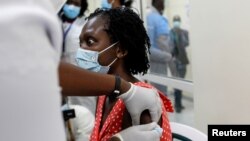 FILE - A woman reacts as she receives a COVID vaccine under the COVAX program at Kenyatta National Hospital, in Nairobi, Kenya, March 5, 2021.