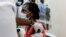 FILE - A woman reacts as she receives a COVID vaccine under the COVAX program at Kenyatta National Hospital, in Nairobi, Kenya, March 5, 2021.