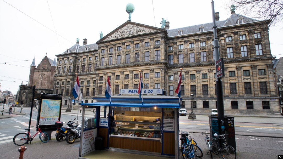 An empty herring stand and deserted streets around noon, outside the Royal Palace, rear, in the center of Amsterdam, Netherlands, March 18, 2020.