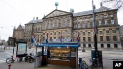 An empty herring stand and deserted streets around noon, outside the Royal Palace, rear, in the center of Amsterdam, Netherlands, March 18, 2020.