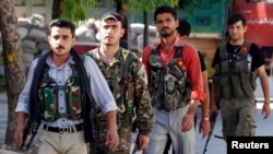 Kurdish fighters from the Popular Protection Units (YPG) walk along a street in Aleppo, June 7, 2013, where they have joined the Free Syrian Army to fight against forces loyal to Syria's President Bashar al-Assad.