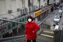 A woman wearing a protective face mask walks past closed restaurants following the coronavirus outbreak in Beijing, March 2, 2020.