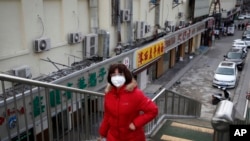 A woman wearing a protective face mask walks past closed restaurants following the coronavirus outbreak in Beijing, March 2, 2020. 