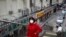 A woman wearing a protective face mask walks past closed restaurants following the coronavirus outbreak in Beijing, March 2, 2020. 