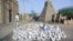In this May 1, 2012 photo, men work alongside one of Timburktu's historic mud mosques, in Mali. 