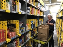 FILE - An employee collects items ordered by Amazon.com customers in a warehouse in San Francisco, Calif., Dec. 20, 2017.