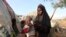 FILE - Rukia Nur feeds her child outside her makeshift dwelling after fleeing famine in the Marka Lower Shebbele regions to the capital Mogadishu.
