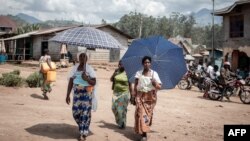 Des femmes déplacées par l'éruption du volcan Nyiragongo marchent dans la rue à Minova, à 50 kilomètres au sud de Goma, la capitale provinciale du Nord-Kivu, le 2 juin 2021.