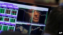 FILE- Specialist Frank Masiello is reflected in his screen on the floor of the New York Stock Exchange, Aug. 24, 2015. 