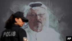 FILE - A Turkish police officer walks past a picture of slain Saudi journalist Jamal Khashoggi prior to a ceremony, near the Saudi Consulate in Istanbul, marking the one-year anniversary of his death, Oct. 2, 2019.