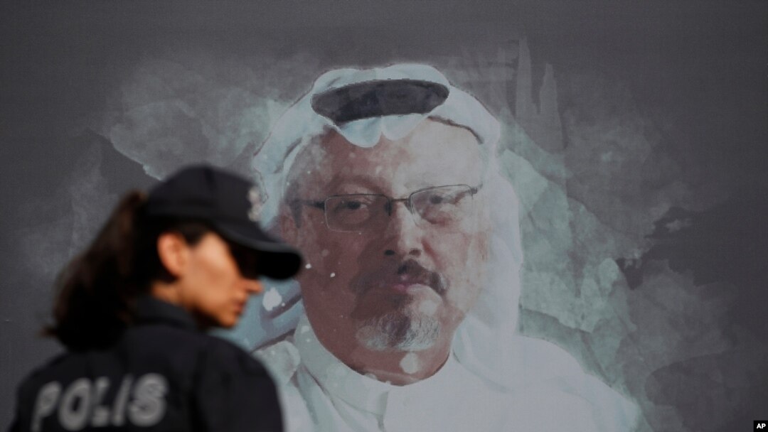 FILE - A Turkish police officer walks past a picture of slain Saudi journalist Jamal Khashoggi prior to a ceremony, near the Saudi Consulate in Istanbul, marking the one-year anniversary of his death, Oct. 2, 2019.