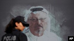 FILE - A Turkish police officer walks past a picture of slain Saudi journalist Jamal Khashoggi prior to a ceremony, near the Saudi Consulate in Istanbul, marking the one-year anniversary of his death, Oct. 2, 2019.