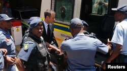 South African Olympic and Paralympic sprinter Oscar Pistorius, center, enters a police van after his sentencing at the North Gauteng High Court in Pretoria, Oct. 21, 2014. 