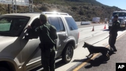 ARCHIVO - Agentes de la Patrulla Fronteriza se apoyan en un elemento canino en la revisión vehicular en un punto de revisión de Pine Valley, California, en la principal vía de Arizona a San Diego, el 14 de diciembre de 2017