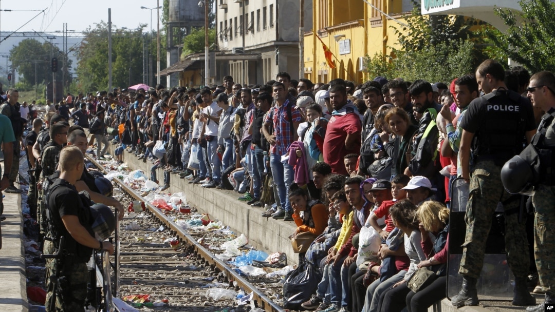 Polisi menjaga jalur kereta sebelum sebuah kereta yang membawa migran ke Serbia memasuki stasiun kereta di kota selatan Makedonia, Gevgelija, 23 Agustus 2015. 