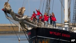 Dutch teens cheer on their schooner Wylde Swan after sailing home from the Caribbean across the Atlantic Ocean when coronavirus lockdowns prevented them from flying, in the port of Harlingen, northern Netherlands, Sunday, April 26, 2020. (AP Photo/Peter Dejong)