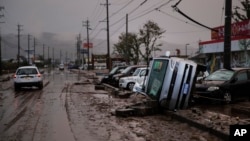 Typhoon-damaged cars sit on the street covered with mud, Oct. 14, 2019, in Hoyasu, Japan. 