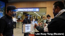 Seorang wisatawan memindai kode QR saat tiba di bandara menyusul pembukaan Langkawi untuk wisatawan domestik di tengah pandemi virus corona COVID-19) di Malaysia, 16 September 2021. (Foto: Lim Huey Teng/Reuters)