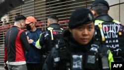 Police question a man outside the West Kowloon Magistrates' court in Hong Kong on November 20, 2024. 