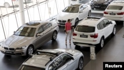 FILE - A woman looks at cars at a BMW dealership in Beijing, July 13, 2015.