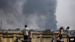 Black smoke billows from the industrial zone of Hlaing Thar Yar township in Yangon, Myanmar Sunday, March 14, 2021. Attacks on Chinese-run factories in Myanmar's biggest city drew demands Monday from Beijing for protection for their property and employees, while many in Myanmar e