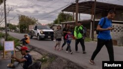 Una familia migrante de Venezuela pasa junto a un hombre comiendo en un puesto al borde de la carretera tras haber sido disuadida por las autoridades locales de cruzar el río Grande hacia Eagle Pass, en Texas, desde Piedras Negras, Coahuila, México el 7 de octubre. [REUTERS]