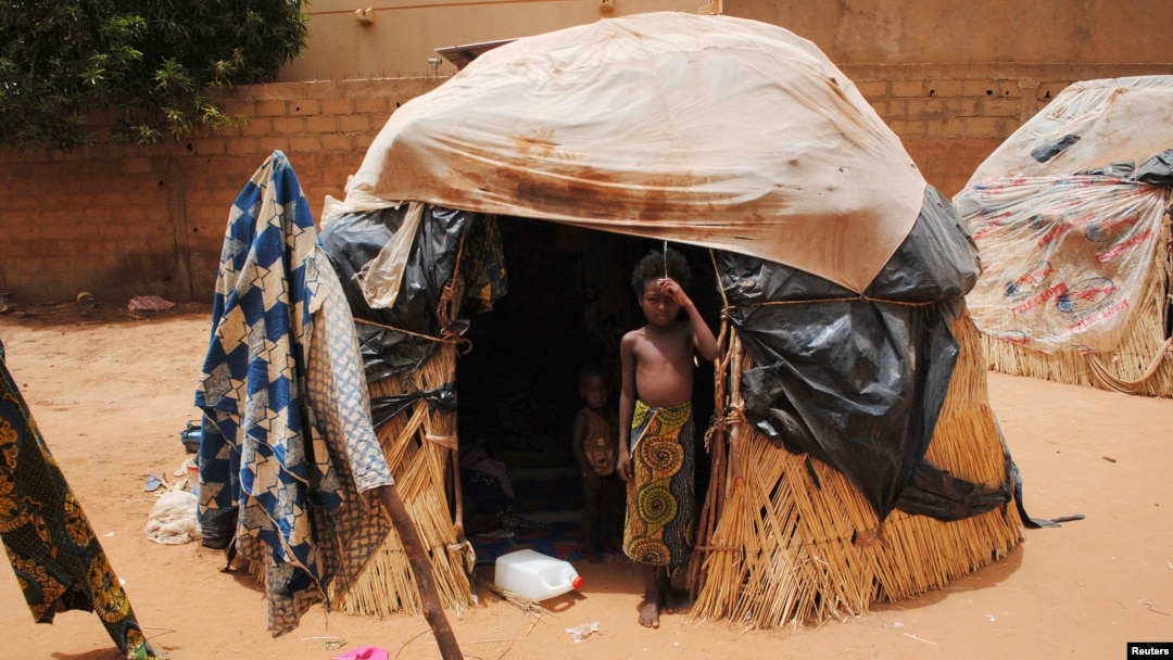 FILE - A girl stands outside a hut in Niger's capital, Niamey. In impoverished Niger, recurring and more intense drought "is absolutely punishing," a U.N. official says.