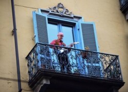 A man plays guitar as part of a flashmob organized to raise morale during Italy's coronavirus crisis in Turin, Italy, March 13, 2020.