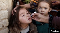 A girl receives polio vaccine drops from a vaccination worker outside her family's home in Quetta, Pakistan, Jan. 2, 2017.