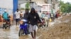 FILE - People walk through a waterlogged street after floods caused by torrential rains, in Port-de-Paix, Haiti, Dec. 23, 2024.