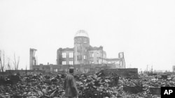 Seorang wartawan perang dari pihak sekutu memperhatikan puing-puing bangunan di Hiroshima setelah kota itu dihancurkan bom atom pada 1945 (Foto: AP Photo/arsip)