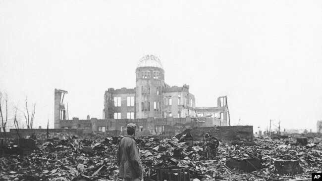 Seorang wartawan perang dari pihak sekutu memperhatikan puing-puing bangunan di Hiroshima setelah kota itu dihancurkan bom atom pada 1945 (Foto: AP Photo/arsip)