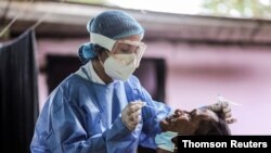 Un miembro del equipo médico de la Cruz Roja Colombiana toma una muestra de hisopo para analizar la enfermedad del coronavirus (COVID-19) de un refugiado venezolano que huyó de su país debido a operaciones militares, en Arauquita.