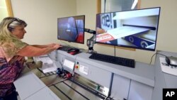 FILE - Election worker Kelly Moselage puts test ballots through a vote-counting machine at the King County elections office in Renton, Wash., Sept. 19, 2018.