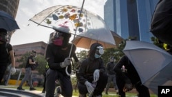 Protestors hold umbrellas as they wait for a possible volley of tear gas at the Hong Kong Polytechnic University campus in Hong Kong, Thursday, Nov. 14, 2019. 